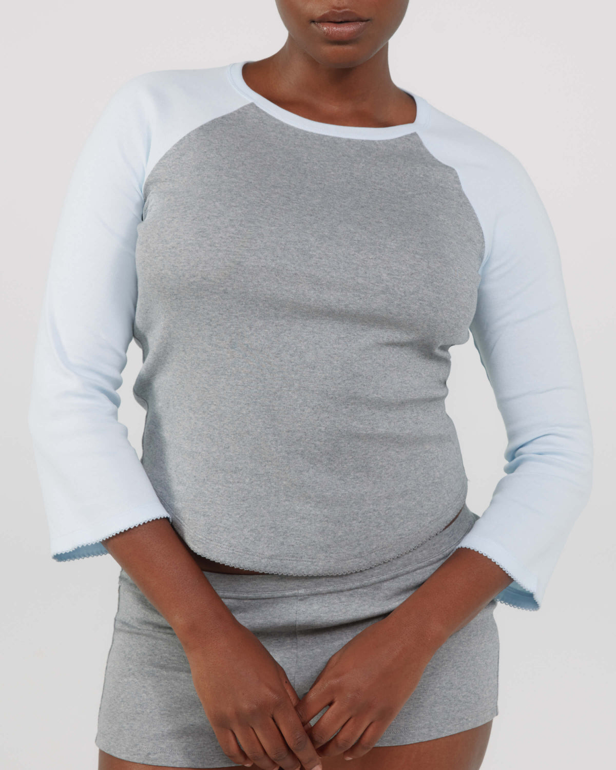 Person wearing a gray and white long-sleeve shirt with a plain background