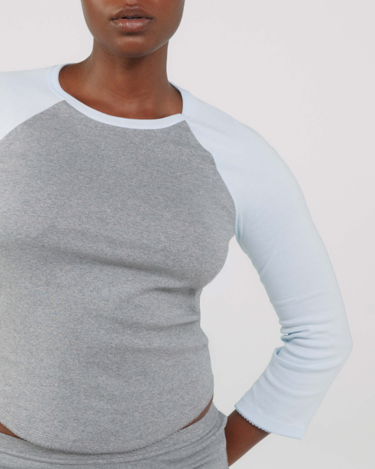 Person wearing a gray and light blue long-sleeve shirt on a plain background