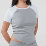 Person wearing a gray and white baseball shirt with gray pants on a light gray background