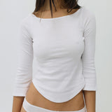 Person wearing a white long-sleeve top and underwear on a plain background