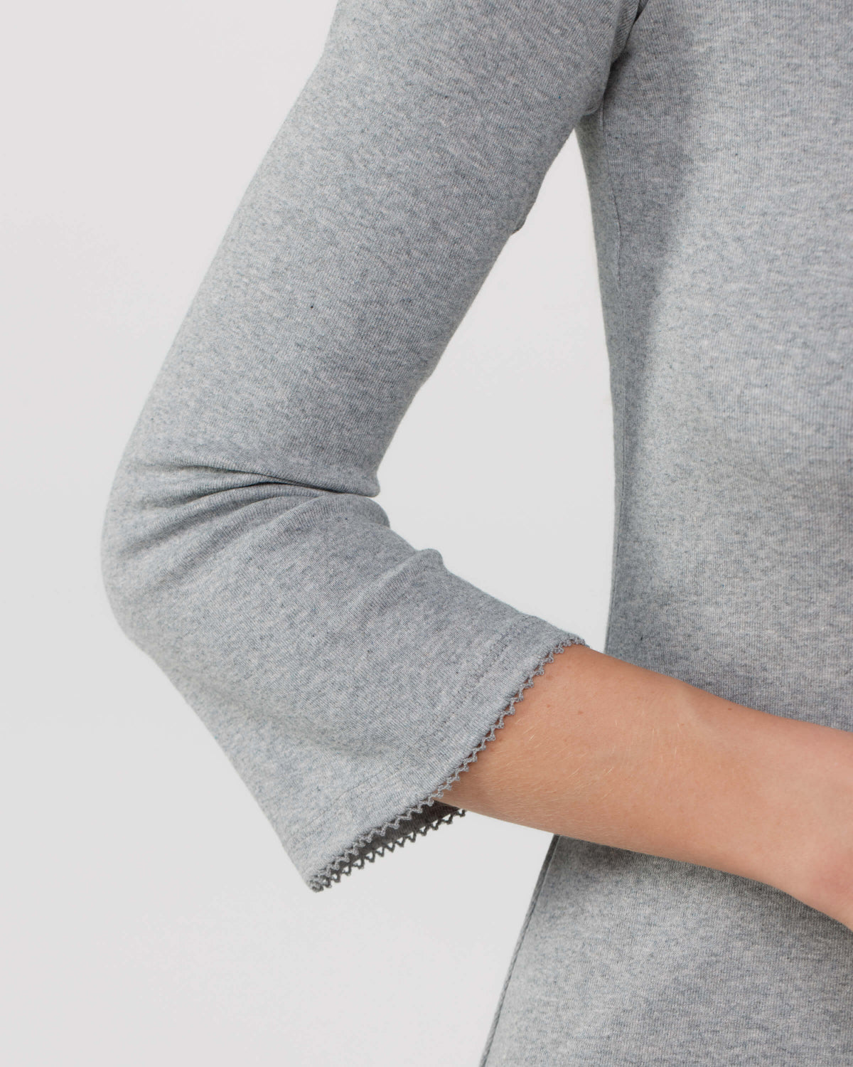 Gray long-sleeve top with a close-up of the sleeve on a light gray background
