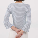 A person shown from the back wearing a long-sleeve top with thin navy and white horizontal stripes, paired with light-colored pants, against a plain light background.