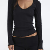 Person wearing a black long-sleeve top and black shorts on a white background