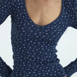 Navy blue long-sleeve top with white floral pattern on a plain background