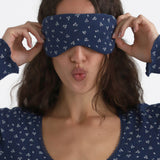 Woman wearing a blue sleep mask with white patterns, posing playfully.