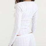 White top with long sleeves and matching trousers on a plain background