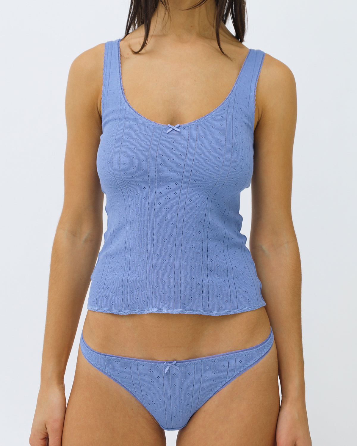 Woman wearing a blue tank and thong set on a white background