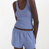 Woman wearing a blue ribbed tank top and shorts set on a white background