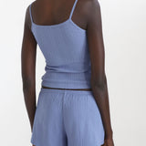 Woman wearing a blue ribbed tank top and shorts set on a white background