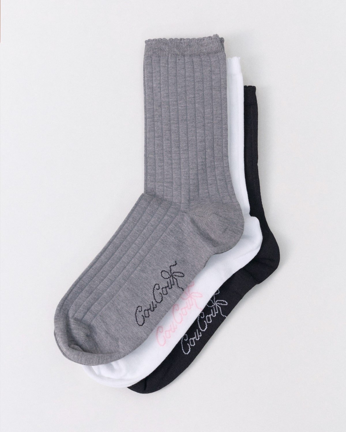 Three socks in gray, white, and black on a light gray background.