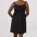 Black slip dress worn by a model on a white background