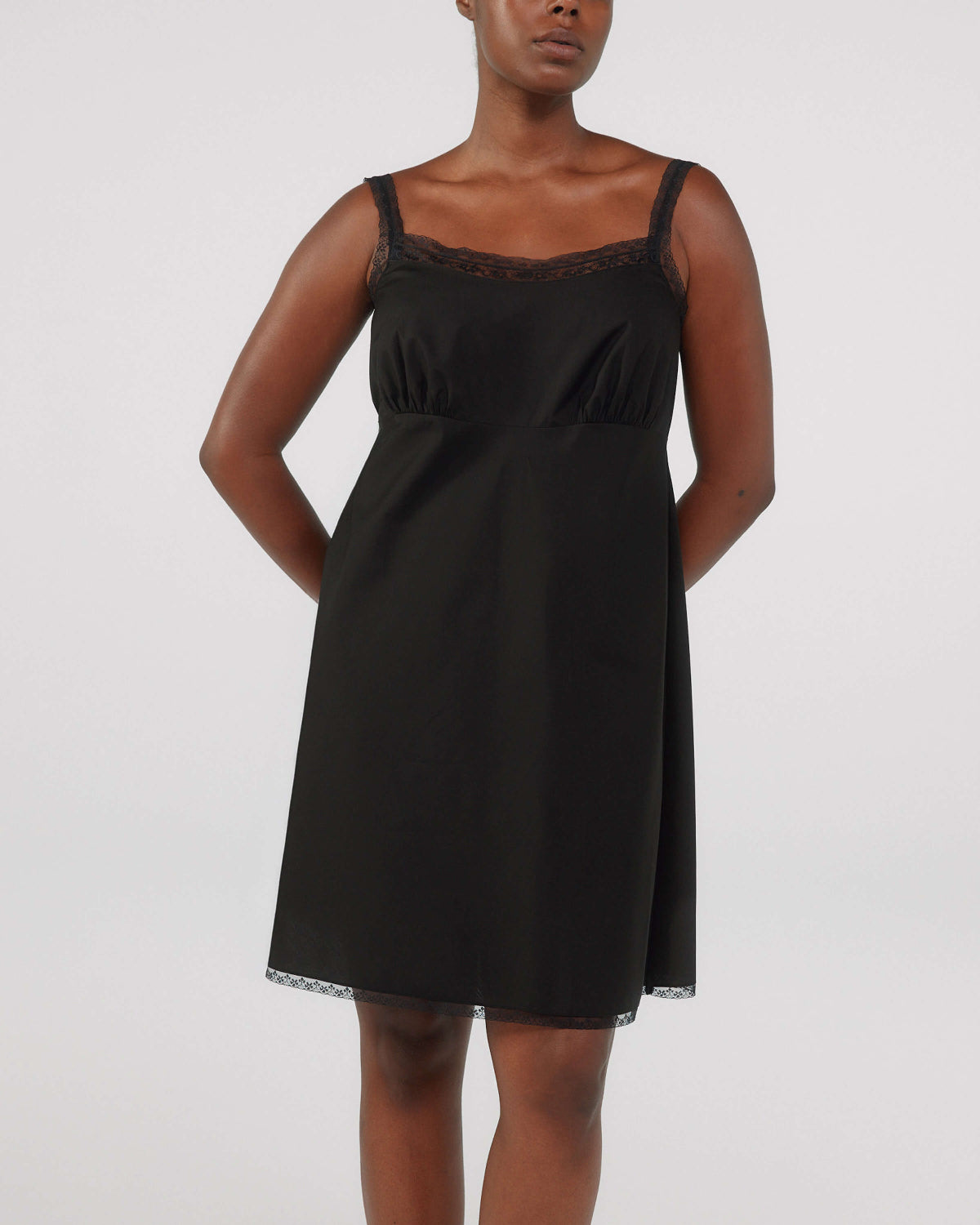 Black slip dress worn by a model on a white background