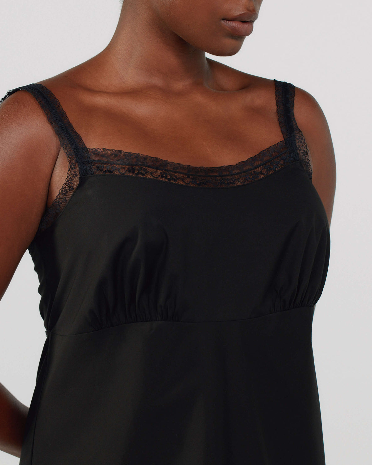 Black slip dress with lace detailing on a plain background