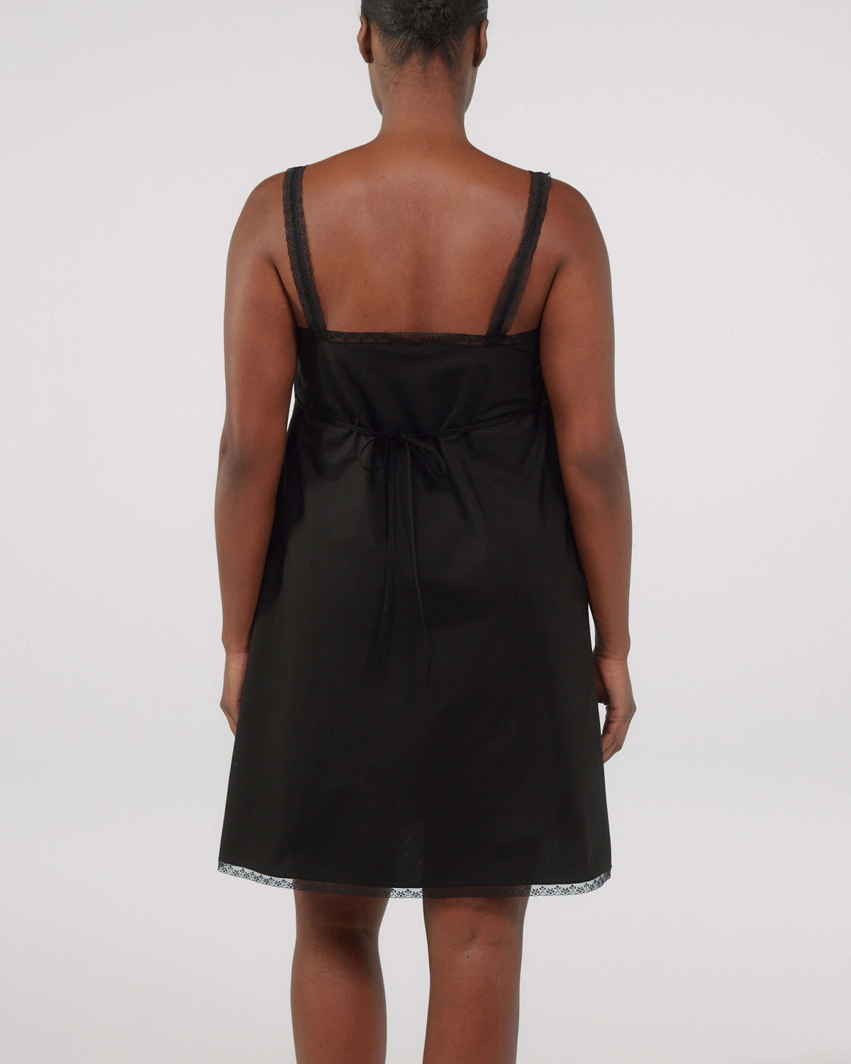 Black slip dress worn by a person on a white background