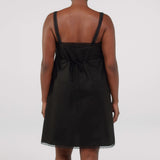 Black slip dress worn by a person on a white background