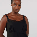 Woman wearing a black dress with lace details on a plain background
