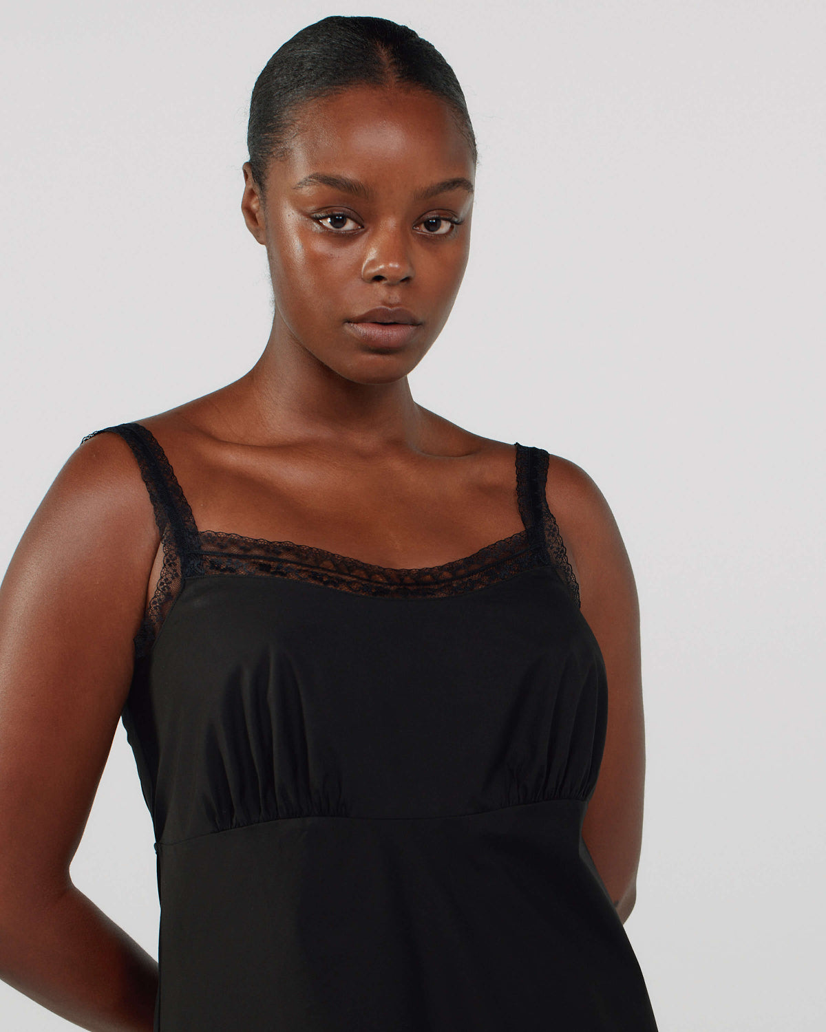 Woman wearing a black dress with lace details on a plain background