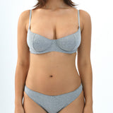 Woman wearing a gray bra and panties set on a white background