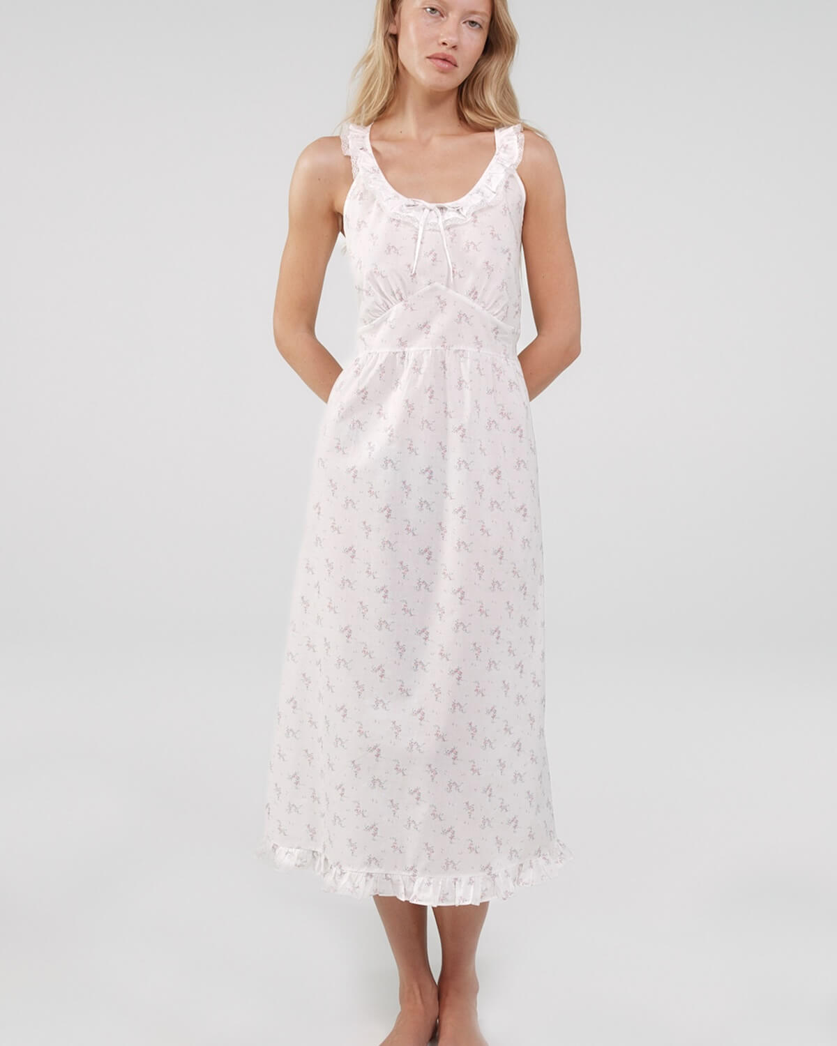 Woman wearing a white lace dress against a plain background