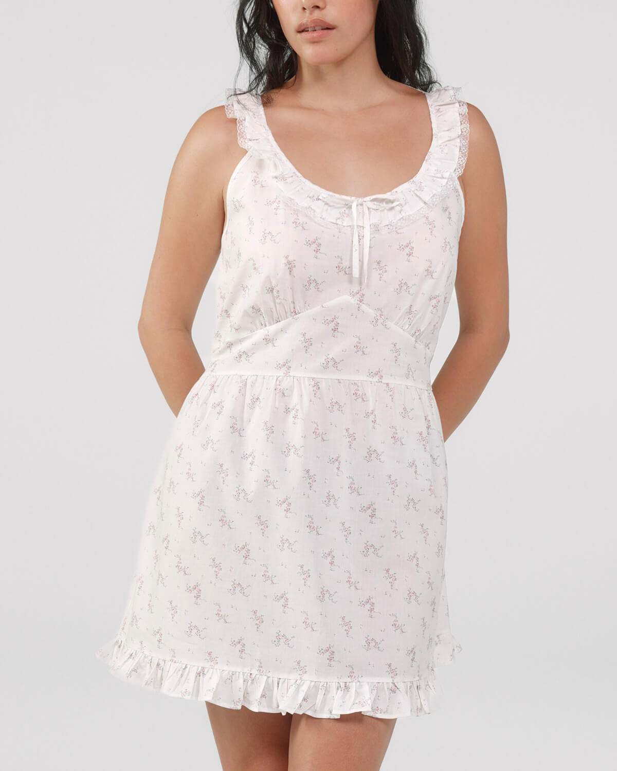 Woman wearing a white floral dress on a plain background