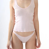 Woman wearing a white ribbed tank top and underwear set on a white background