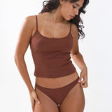 Woman wearing a brown tank top and underwear set on a white background