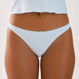 Light blue thong worn by a person on a plain background