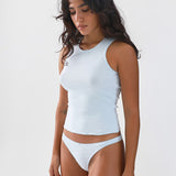 Woman wearing a light blue sleeveless top and thong on a white background