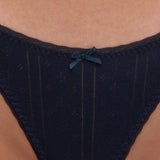 Close-up of a person wearing a dark navy blue lace thong with a small matching bow at the center front.