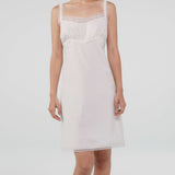 Woman wearing a white slip dress on a plain background