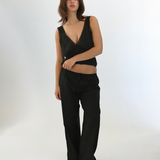 Woman wearing a black sleeveless top and pants on a white background