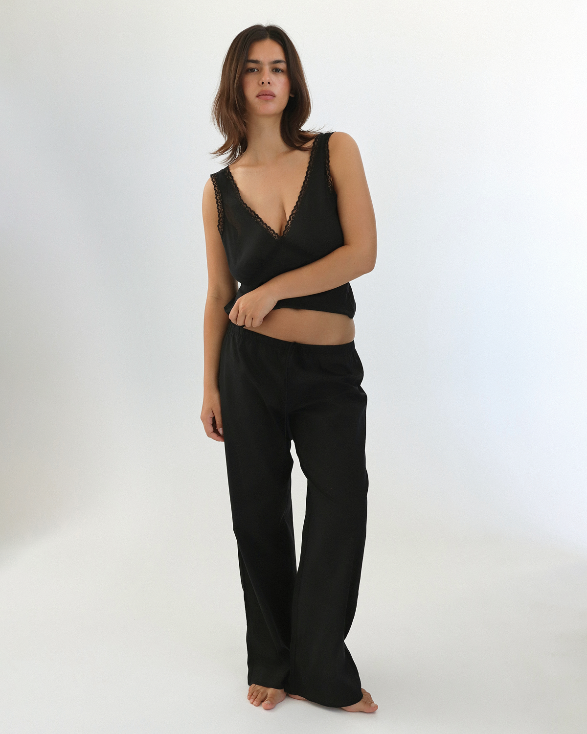 Woman wearing a black sleeveless top and pants on a white background