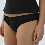 Person wearing black briefs on a plain background
