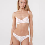Woman wearing a white lace bra and panties set on a plain background