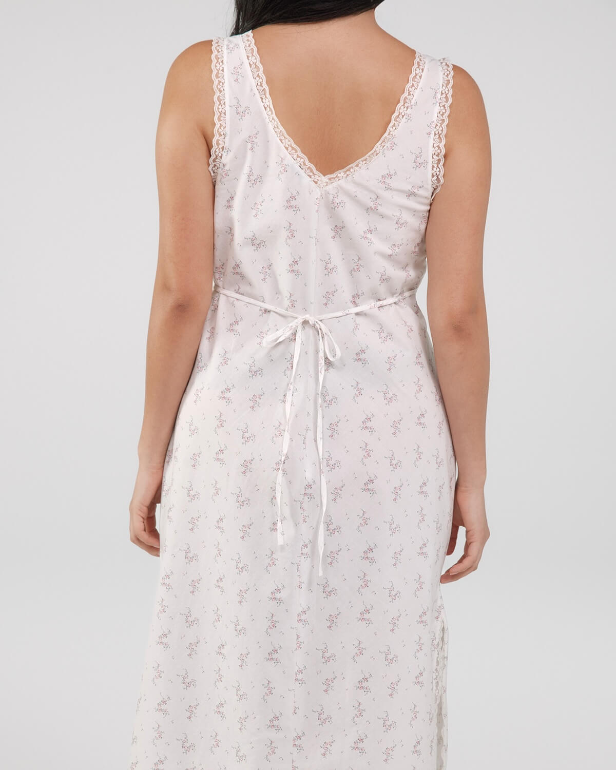 White floral dress worn by a person on a plain background