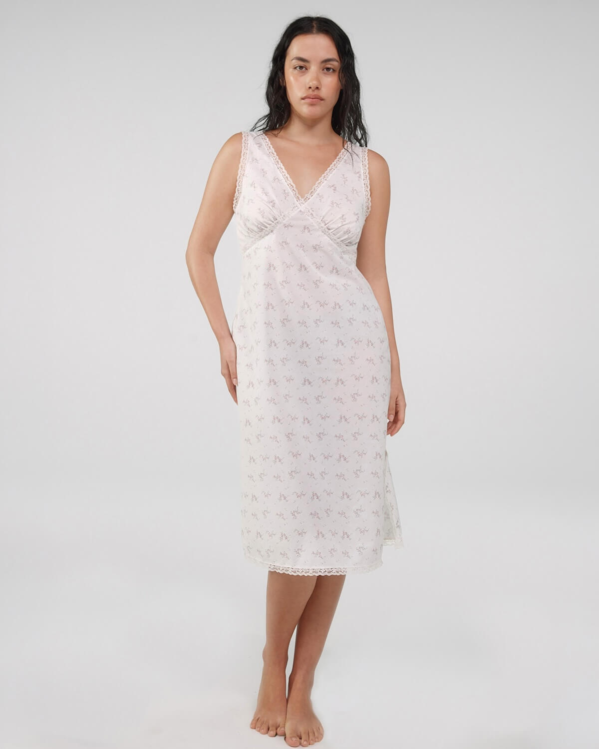 Woman wearing a white lace nightgown against a plain background