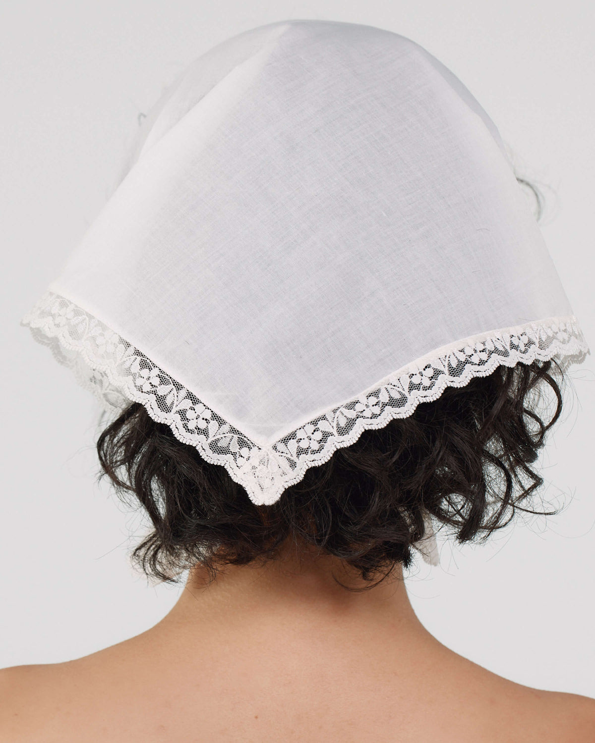 White bonnet with lace trim on a plain background