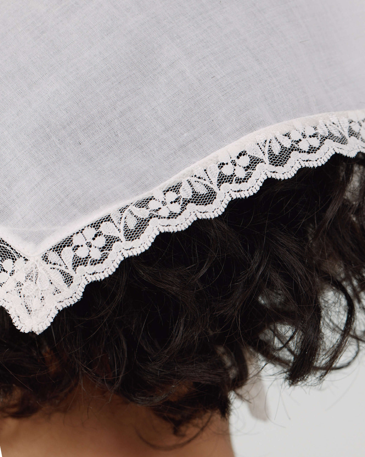 Close-up of a lace-trimmed headscarf with a neutral background