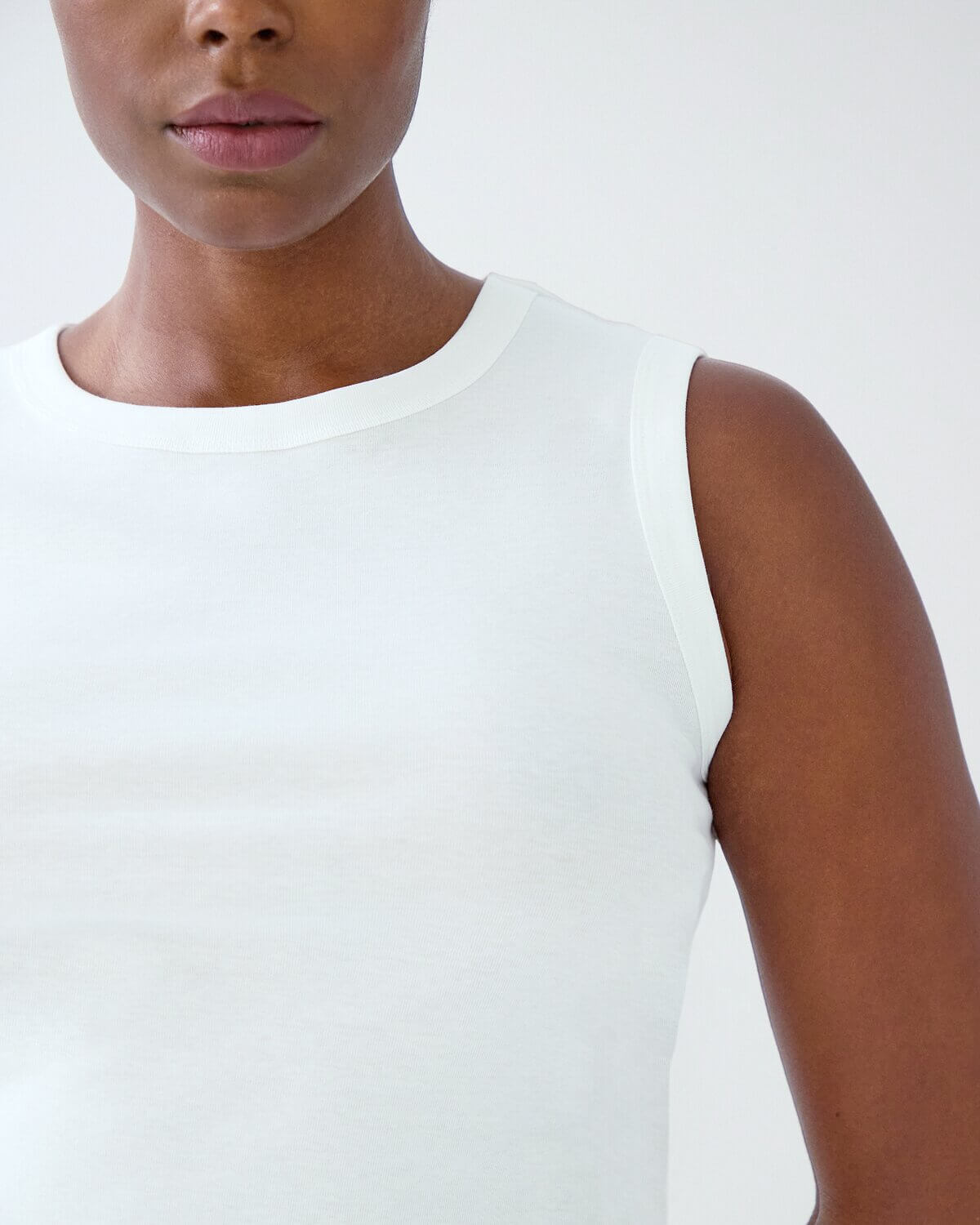 White sleeveless top worn by a person on a white background
