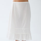 White skirt worn by a person on a plain background